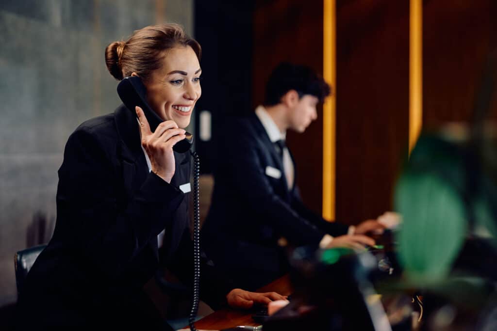 female hotel receptionist answering phone at front desk 