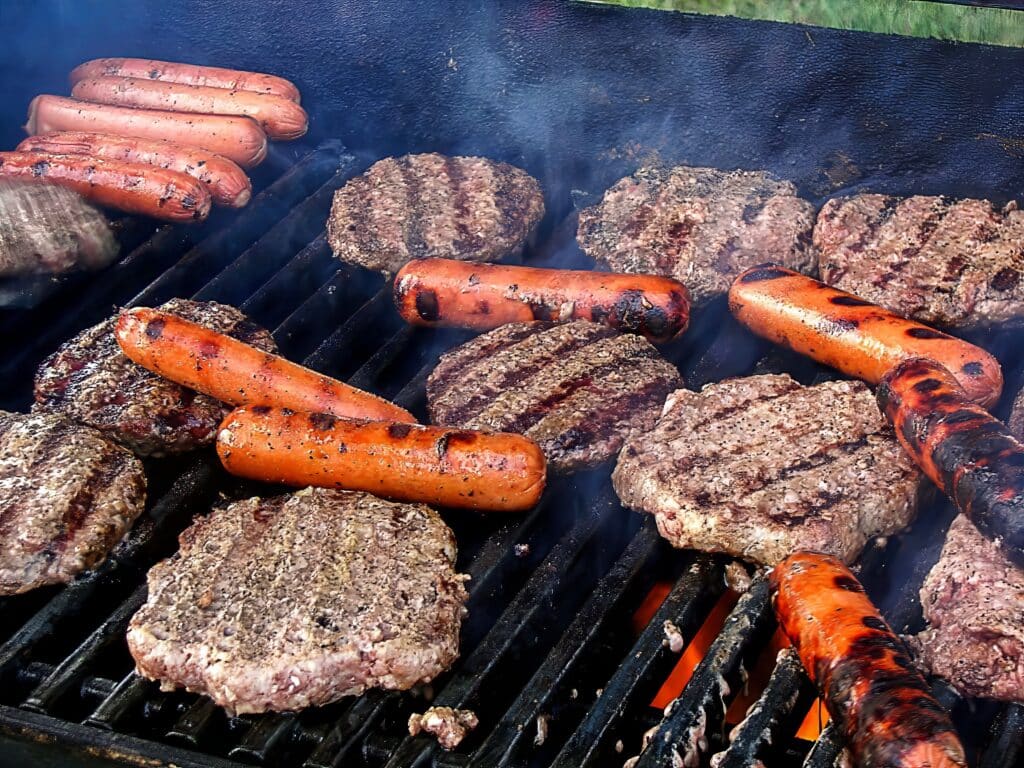 hot dogs and burgers on grill for football tailgate cookout