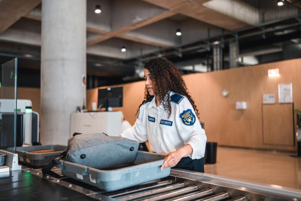 TSA agent inspecting a passenger's bag at an airport security checkpoint