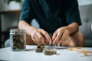 How to Roll the Perfect Joint in 5 Easy Steps 2 Selective focus and close up hands of young man preparing to smoking marijuana joint Cannabis in living room at home, he rolling a cannabis on paper, dry weed blunt in bottle on table