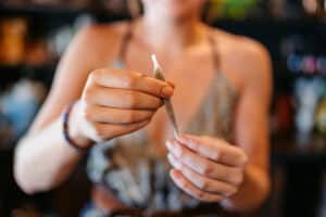 How to Roll the Perfect Joint in 5 Easy Steps 4 Young female retail worker making a joint using herbal cannabis (marijuana) in a cannabis shop in Thailand. Close-up.